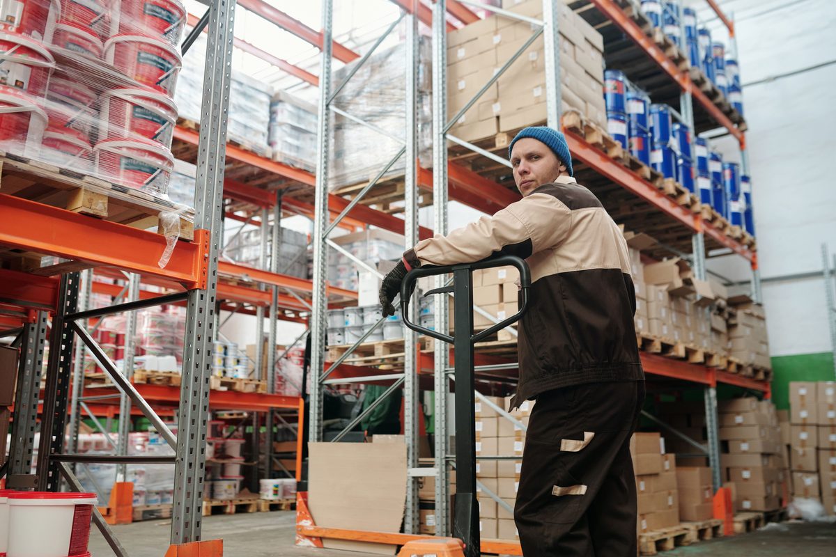 Operador usando patín hidráulico para mover producto
